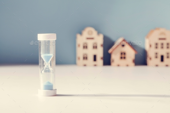 housing mortgage, property market , demand for real estate concept. hourglass and small toy houses