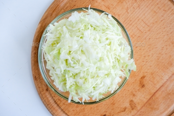 Shredded white cabbage on a wooden board. Fermentation of vegetables. Healthy food. Flat lay.