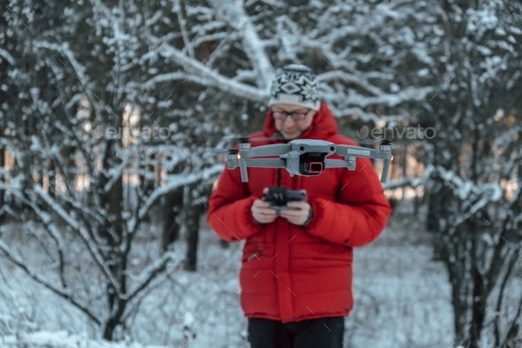 Man controls a quadcopter in winter forest. Shooting nature from drone. Focus on the drone. Close-up
