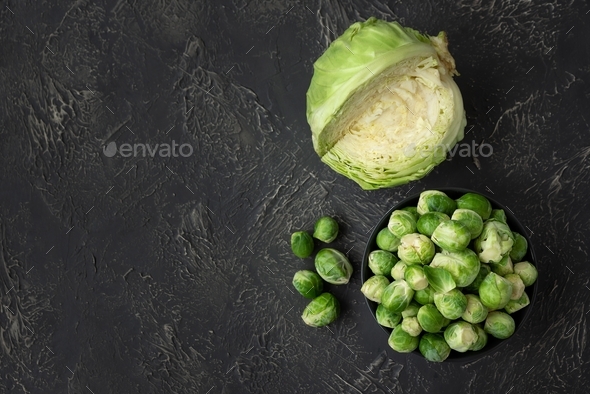 Close-up bowl with raw brussels sprouts and cabbage on concrete background. Vegetarian food