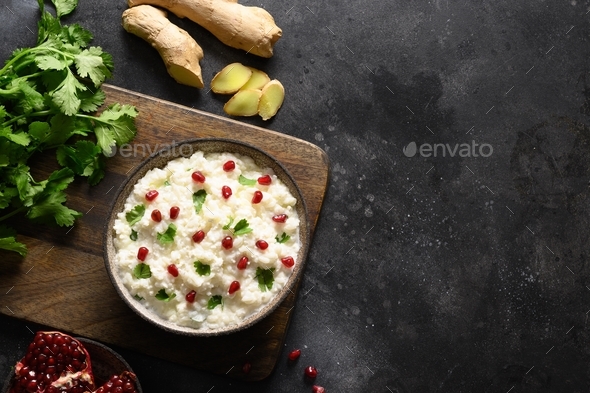 Curd Rice with pomegranate, cilantro, mustard seeds, ginger on a black background. Indian cuisine