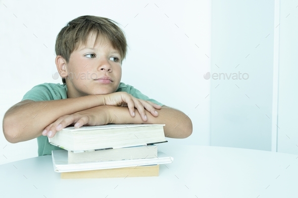 A sad boy in a green T-shirt, a student with a stack of books teaches lessons Difficulties of school