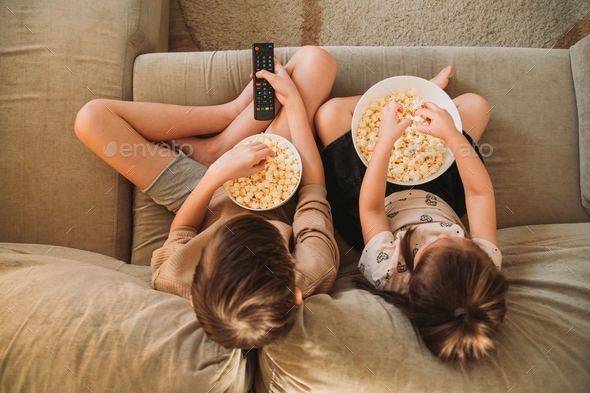 children sit on the couch, turn on the TV and eat popcorn