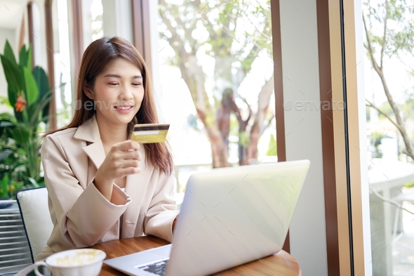 attractive Asian businesswoman using credit card for goods payments shopping online by laptop