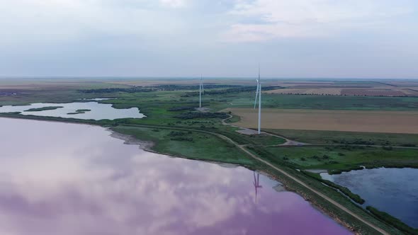 Wind turbines on the shores of a beautiful pink lake.