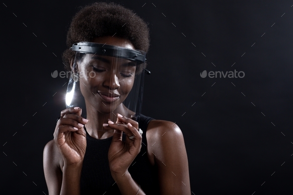African american woman in transparent protective face mask shield on black background.