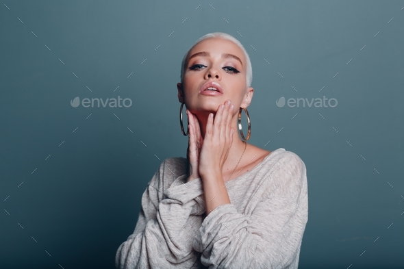 Millenial young woman with short blonde hair portrait doing face yoga self facebuilding massage for