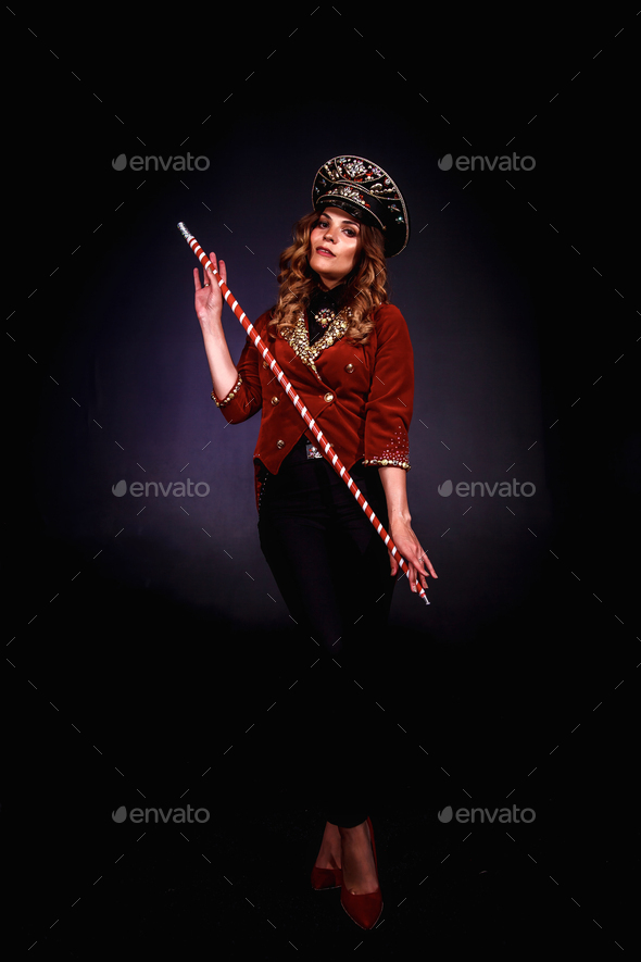 Female magician illusionist of circus with cane showing soap bubbles show at black background