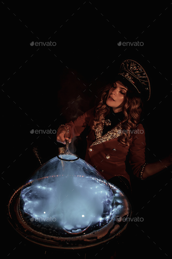 Woman magician illusionist of circus showing soap bubbles show on tabletop at black background
