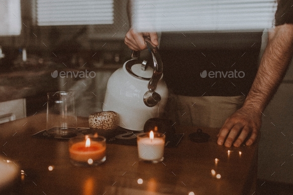 a young man makes tea and pours boiling water over Chinese tea puerh, candle light
