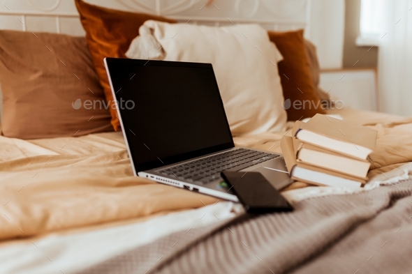 laptop on cozy bed with books in bedroom - Stock Photo - Images
