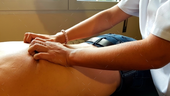Female physical therapist assinting a patient while giving treatment massaging the back
