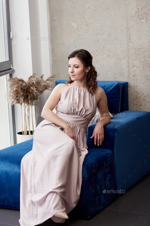 Aesthetic girl in dress in elegant Scandinavian apartments sitting on the blue sofa