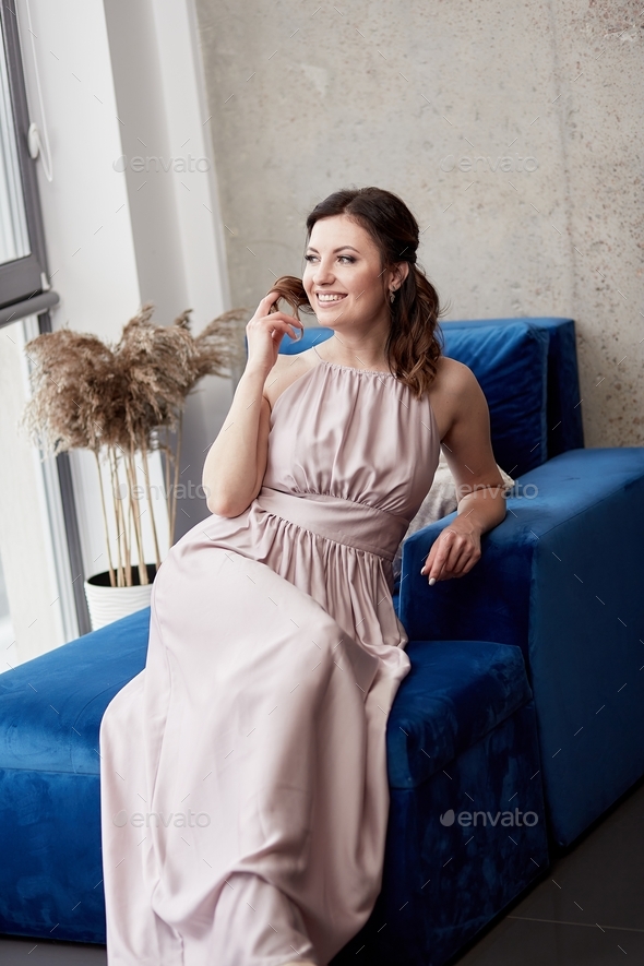 Aesthetic girl in dress in elegant Scandinavian apartments sitting on the blue sofa