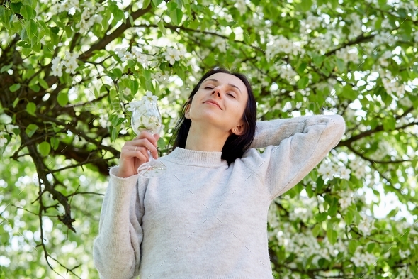 Aesthetic girl holds glass of flowers, spring blooming tree. Spring breath. Connecting with nature