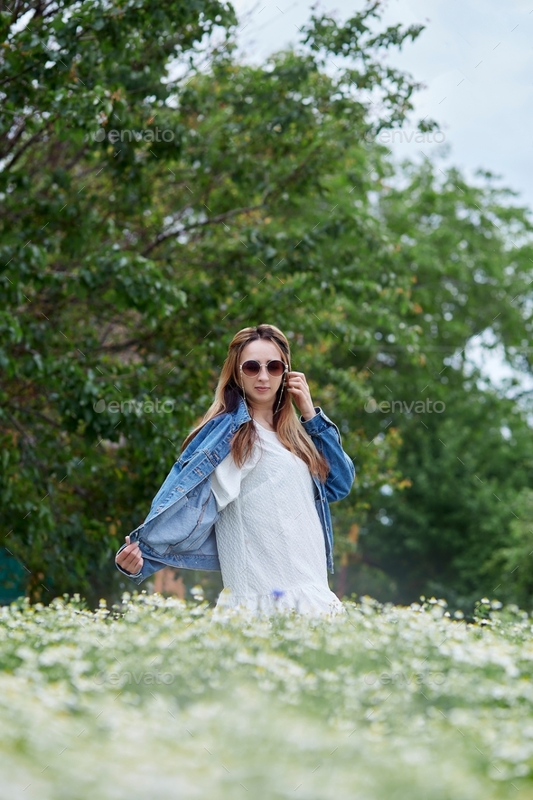 Aesthetic millennial girl in chamomile field relaxing, connecting with