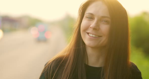 Portrait of Beautiful Girl Smiling and Looking at Camera During Sunset alt