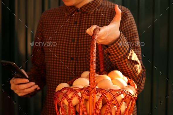 Many eggs in basket. Young woman holding whole basket of brown organic eggs on modern green backgrou