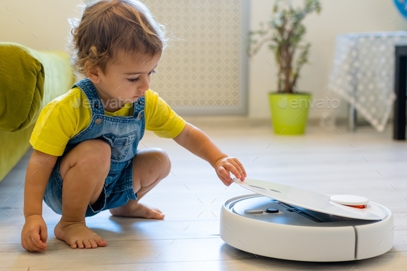 child starts a robot vacuum cleaner