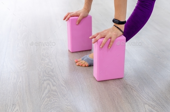 Close-up a woman leans her palms on pink yoga blocks. concept yoga accessories and equipment