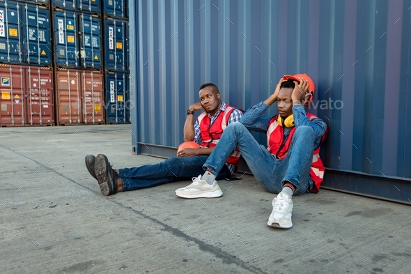 worker men sit close to cargo container and he look tired and sleepy or lost