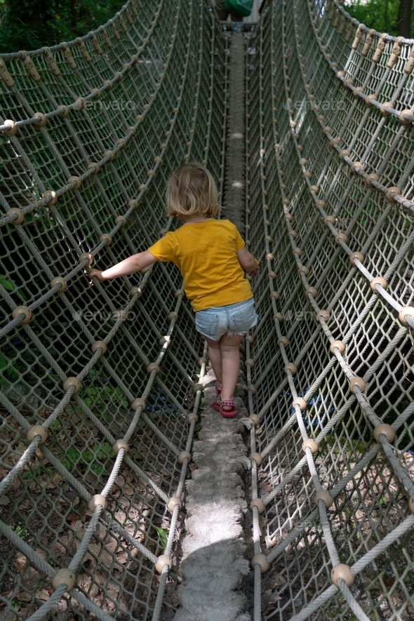 Child on jungle gym at park, walking along the balance beam with ...