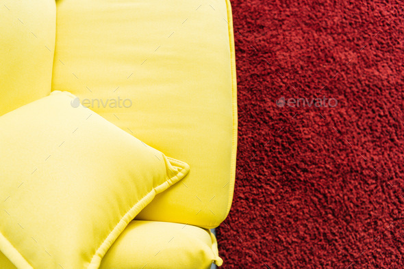 Top view of yellow leather couch and red fluffy rug
