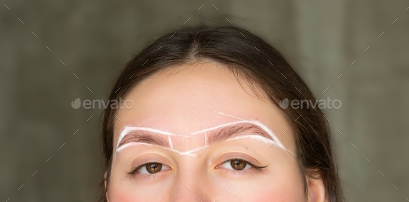 Close-up of female eyebrows with white paste for marking eyebrows in a beauty salon close-up