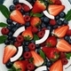 A plate of fresh, ripe berries: blueberries, strawberries, raspberries, cut coconut, mint leaves. - PhotoDune Item for Sale