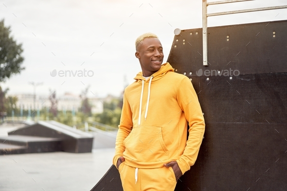 African-american smiling black man yellow hoodie outside Happy emotional afro model guy walking skat