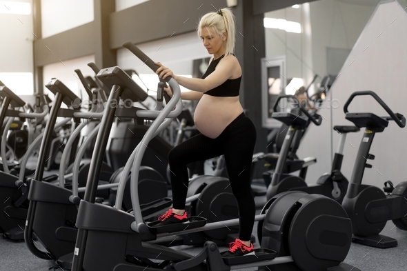 Pregnant Woman training elliptical machine in gym Cardio exercises on elliptical trainer Health life