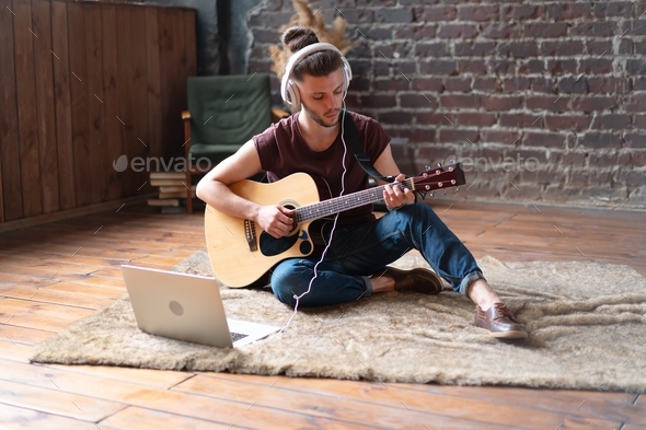 Young Handsome Man watching guitar tutorial on laptop Online courses guitar playing