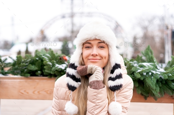 Woman in fluffy fur hat winter jacket sitting outdoor . Christmas mood