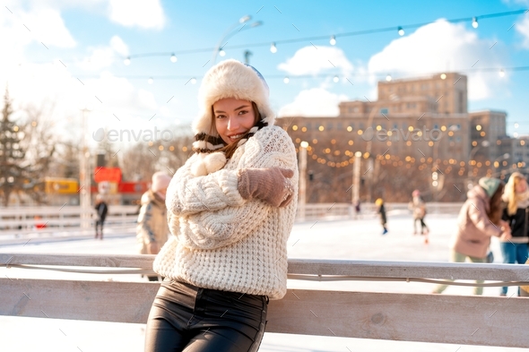 Woman in fluffy fur hat and white sweater smile standing outdoor. Christmas mood Happy people