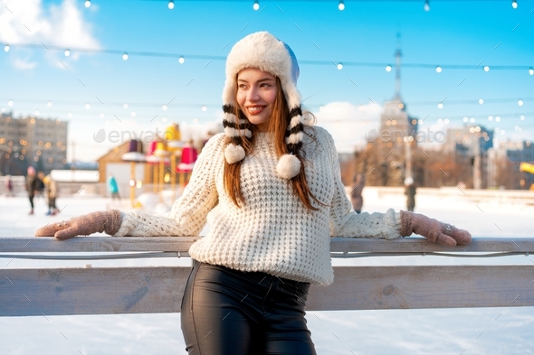 Woman in fluffy fur hat white sweater standing outdoor. Christmas mood. Happy people