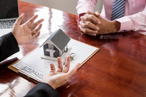 A real estate agent with a home model is talking to clients about renting a home and buying home - Stock Photo - Images