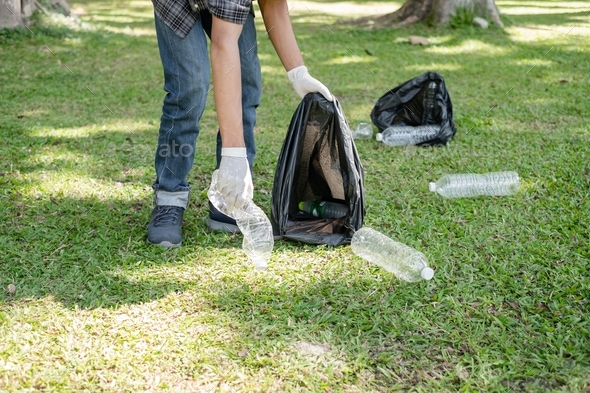 Man's hands pick up plastic bottles, put garbage in black garbage bags to clean up at parks, avoid - Stock Photo - Images