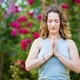Woman doing outside yoga surrounded by blooming roses in a park setting - PhotoDune Item for Sale