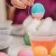 Young millennial Mother at home helping daughter paint colorful Easter eggs for playing and eating - PhotoDune Item for Sale