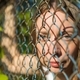 The girl in the park looks through a metal fence. - PhotoDune Item for Sale