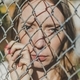 Close-up. The face of a young girl behind a metal fence - PhotoDune Item for Sale