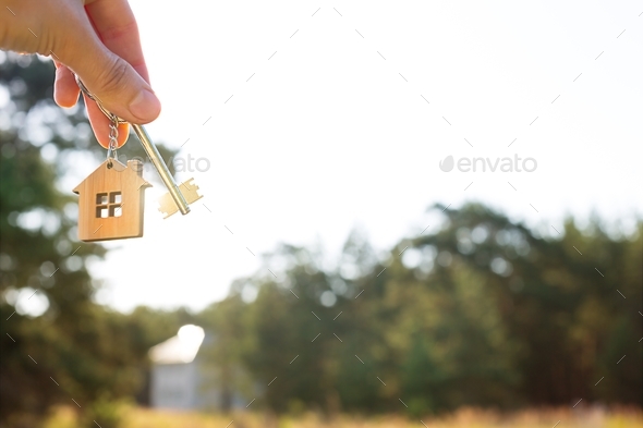 Wooden pendant of a house and key. Background of countryside, nature. Dream of home, building, deliv - Stock Photo - Images