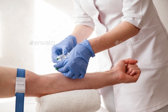 The nurse draws blood from a vein for test.