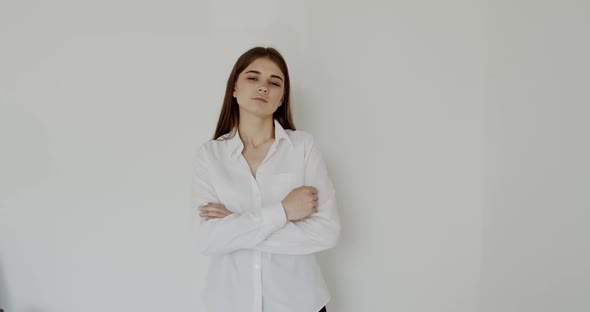 Confident Young Girl Crossing Hands and Looking at Camera on White Background alt