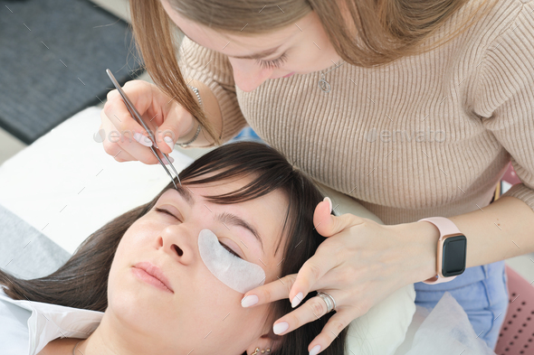 woman cosmetologist applying under eye patch to isolate eyelashes during lash extension procedure. - Stock Photo - Images