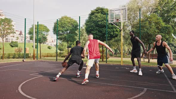 Group of Multiracial Young People Playing Basketball on Court at Outdoors alt