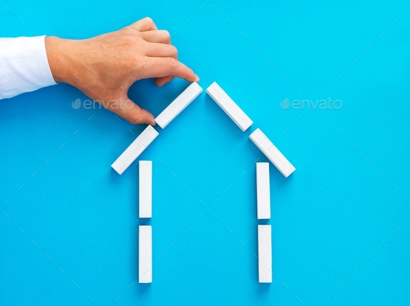 : Businessman making a house of wooden blocks. Eeal estate market concept. - Stock Photo - Images