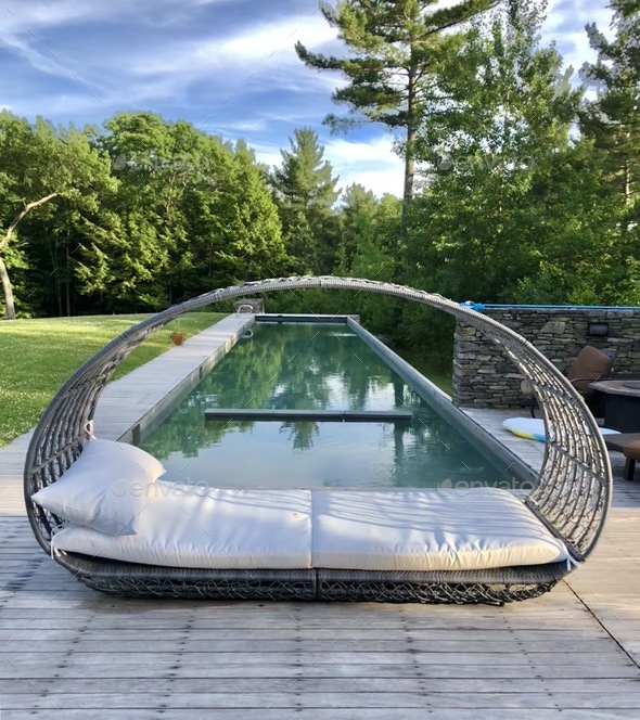 Elegant daybed in front of a long, narrow lap pool. Stock Photo by