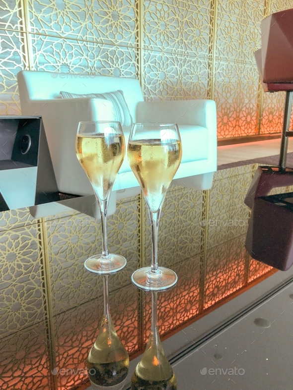 Two champagne flutes filled with bubbly in a luxe, first class airport