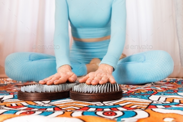 nail therapy on the Sadhu board. a girl in a blue suit holds her hands on nails on a sahu board Yoga